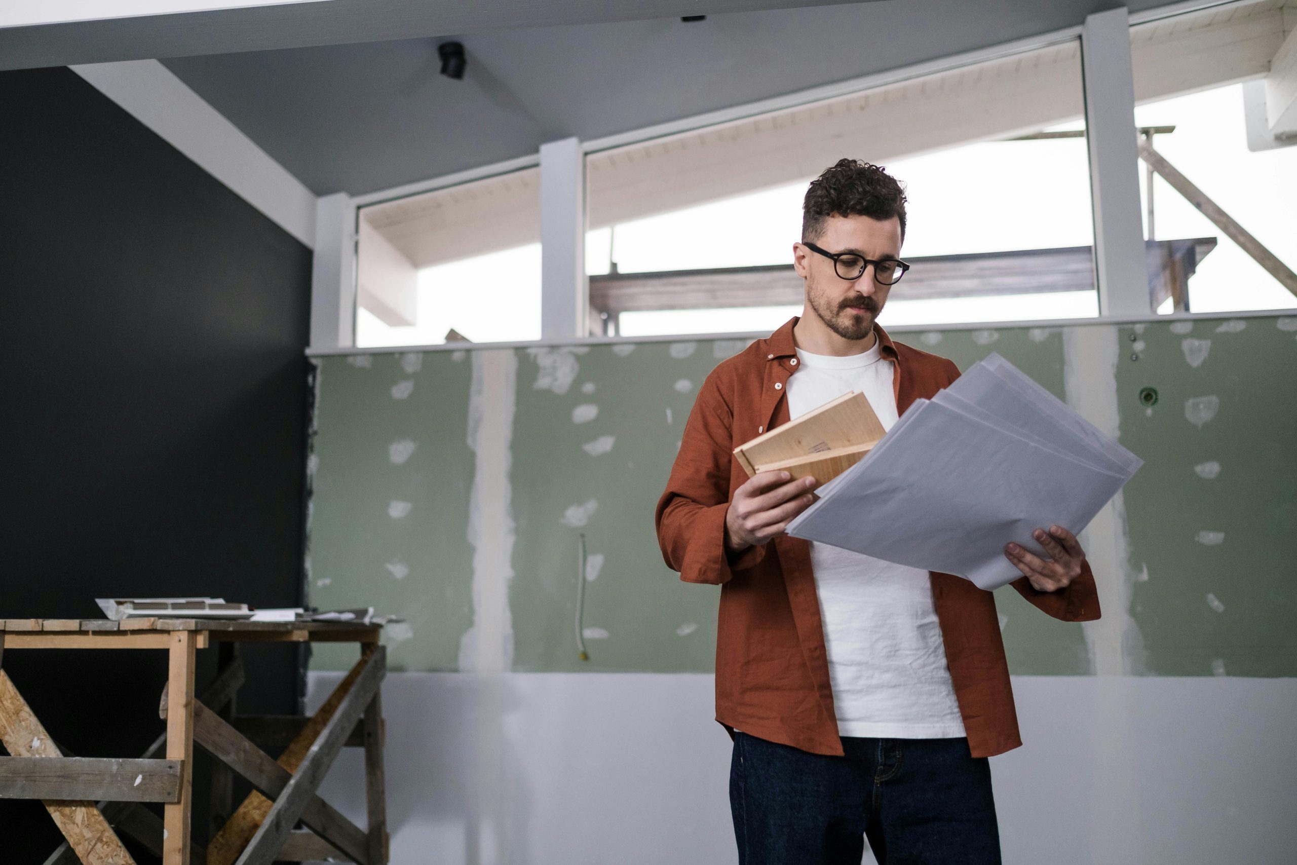 man looking at plans in a house under renovation