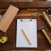 carpentry tools, pencil, and clipboard on a wooden desk