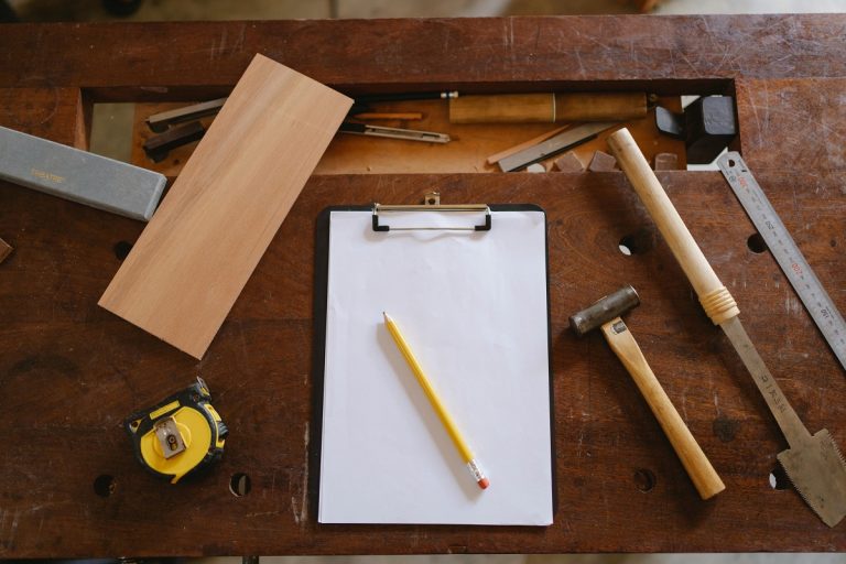 carpentry tools, pencil, and clipboard on a wooden desk